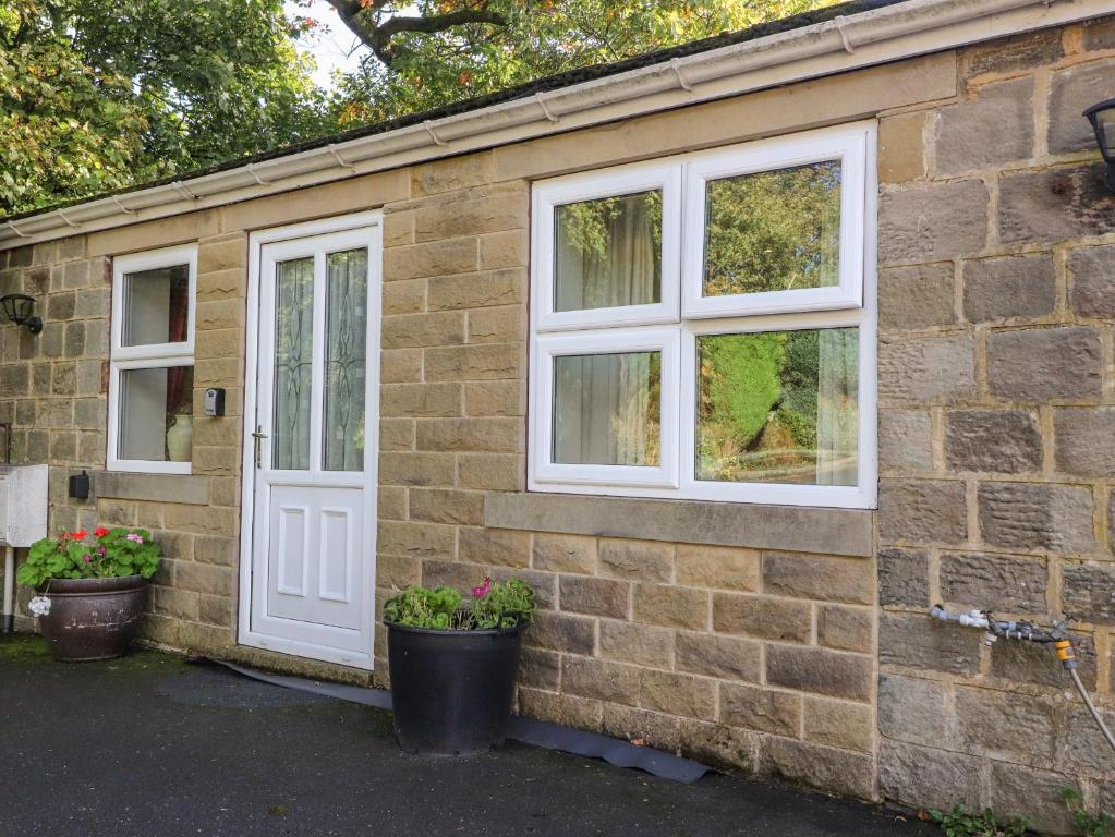 a brick house with two windows and a door at Bronte Cottage in Keighley