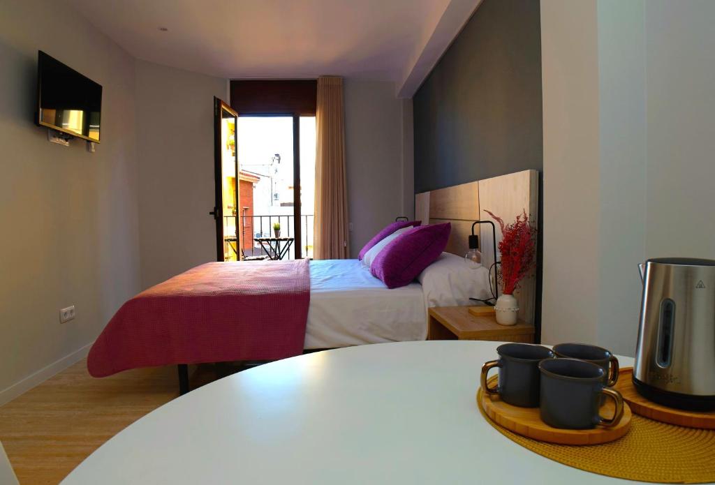 - une chambre avec un lit doté d'oreillers violets et d'une table dans l'établissement Can Mir Badalona, à Badalona