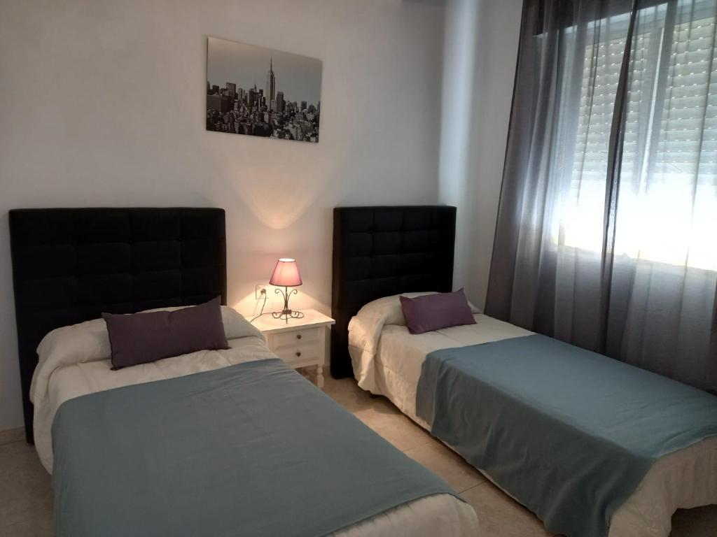 sypialnia z 2 łóżkami, oknem i lampką w obiekcie Centric apartment in Malaga w Maladze