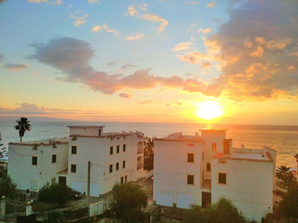 een zonsondergang boven een stad met witte gebouwen en de oceaan bij La dolce vita, relax & kite Falerna in Falerna