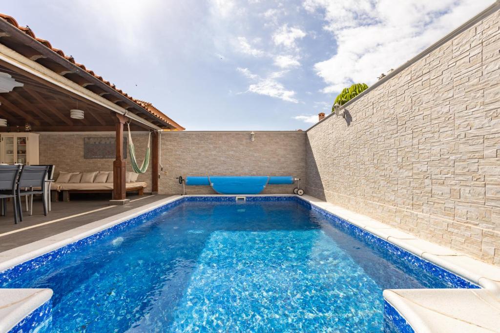 a swimming pool in a backyard with a brick wall at LUXURY VILLA PLAYA DUQUE, PRIVATE POOL & AIRCON, Costa Adeje, Tenerife in Adeje