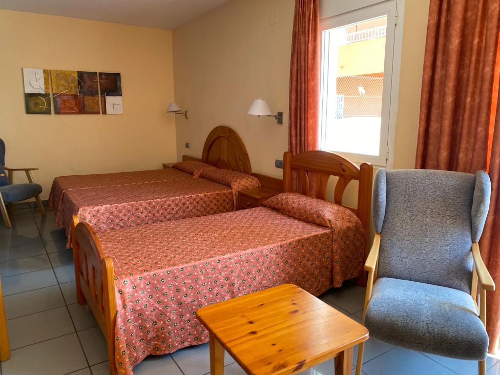 ein Hotelzimmer mit 2 Betten und einem Stuhl in der Unterkunft El Pinche de Oro in Benicarló