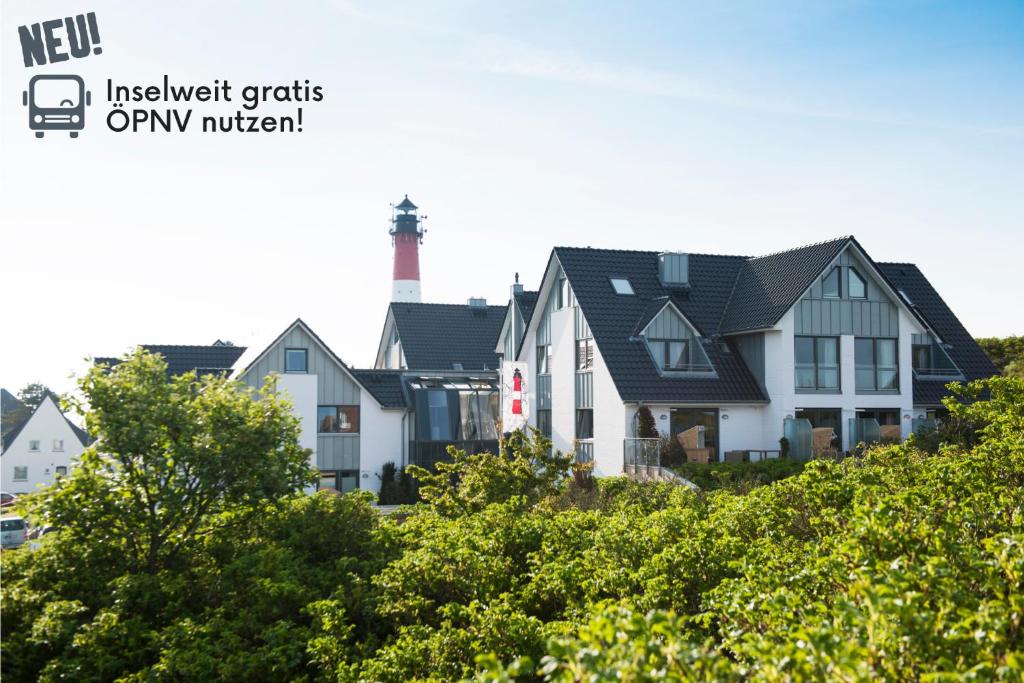 a row of houses with a lighthouse in the background at Apartmenthotel am Leuchtturm in Hörnum