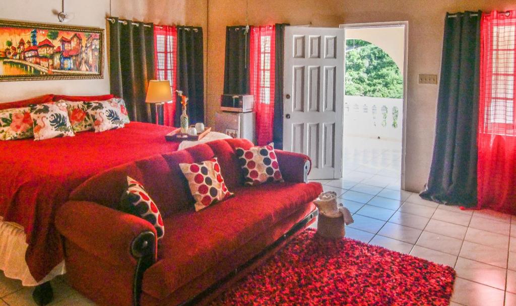1 dormitorio con cama roja y sofá en 876 JA Oasis & Homestay - by Kingston Airport, en Kingston