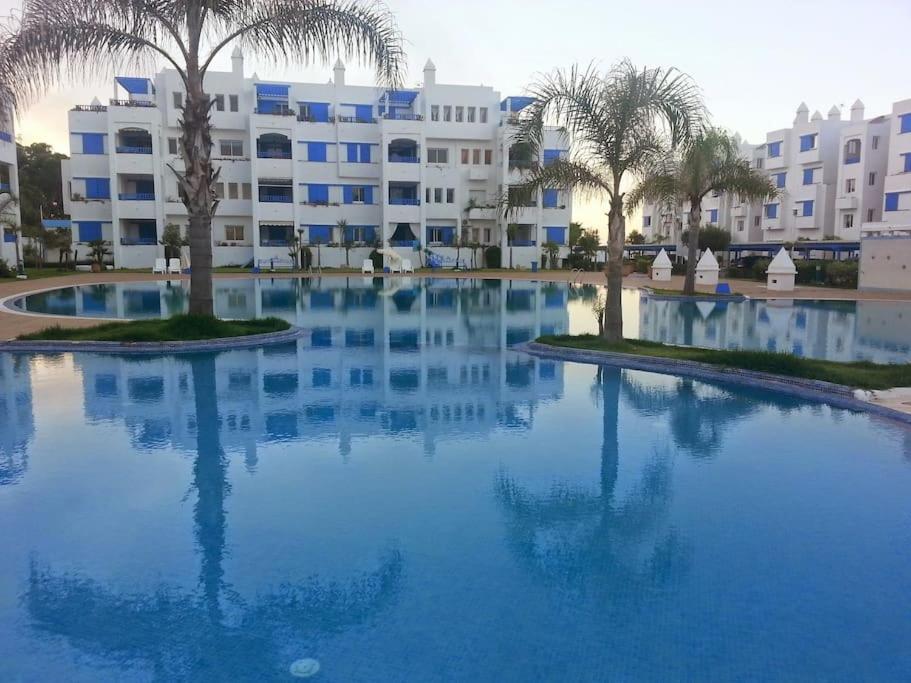 einem großen Pool mit Palmen vor einem Gebäude in der Unterkunft Superbe appart 3pieces a sania plage MARINA SMIR in Mʼdik