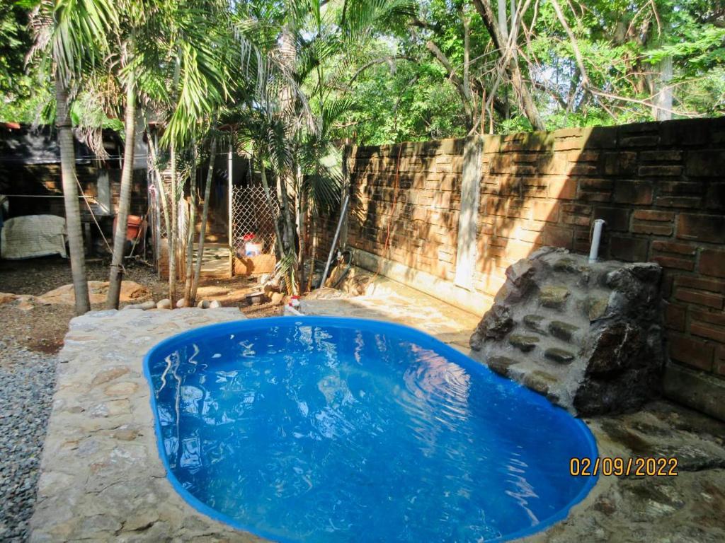 a blue pool in a yard with a brick wall at Casita Monarca in Troncones