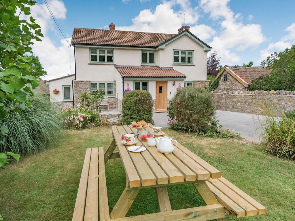 a wooden picnic table in front of a house at Pennyard House in Banwell