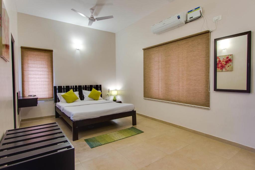 sypialnia z łóżkiem z żółtymi poduszkami i oknem w obiekcie Corner Stay Serviced Apartment-Racecourse w mieście Coimbatore