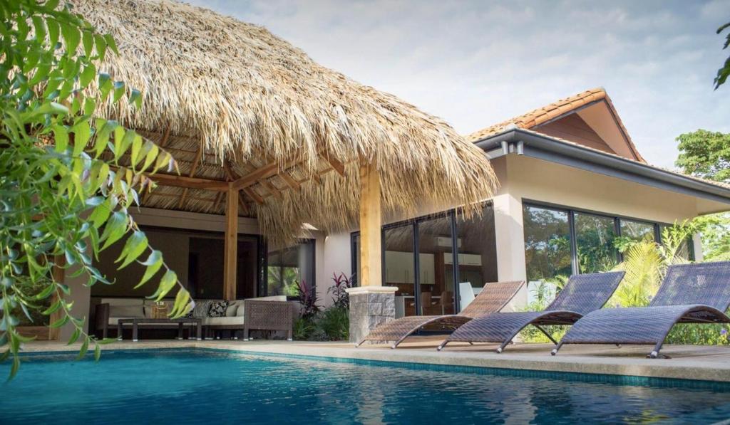 eine Villa mit einem Pool und einem Strohdach in der Unterkunft Casa Oceana-8 BR Luxury Home, Breakfast Included! in Tamarindo