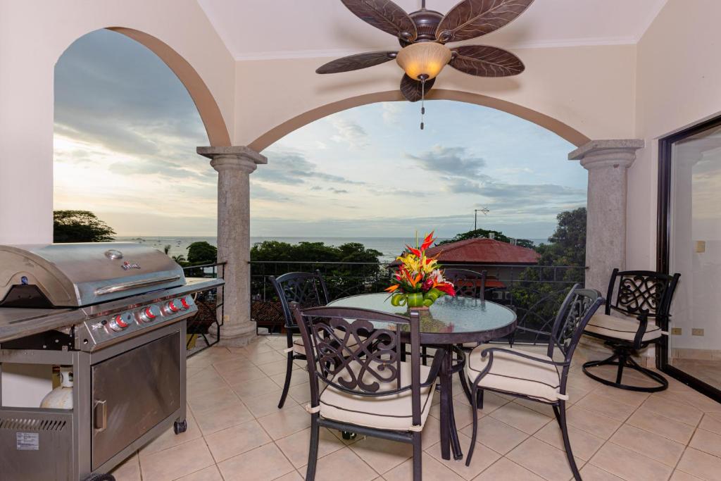 eine Terrasse mit einem Tisch und einem Grill sowie einem Tisch und Stühlen in der Unterkunft Sunrise 48- 3 Bedroom Ocean View Penthouse Condo in Tamarindo