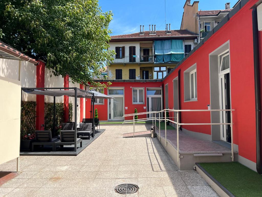 - un bâtiment rouge avec des chaises et des parasols dans une cour dans l'établissement Hostel Turin Metro Young, à Turin