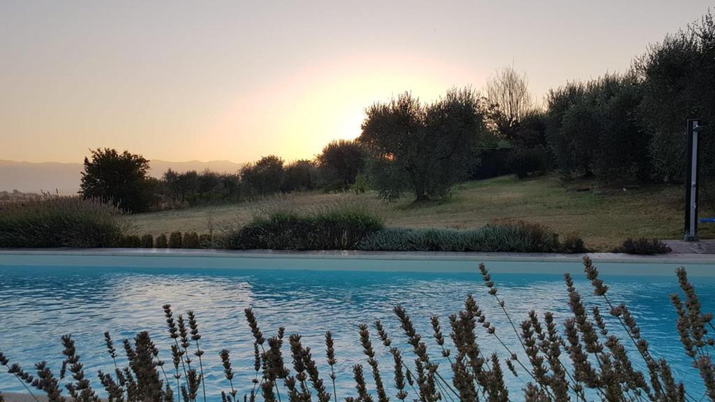einen Pool mit Wasser und Sonnenuntergang im Hintergrund in der Unterkunft Villa di Elisabeth in Marciano Della Chiana