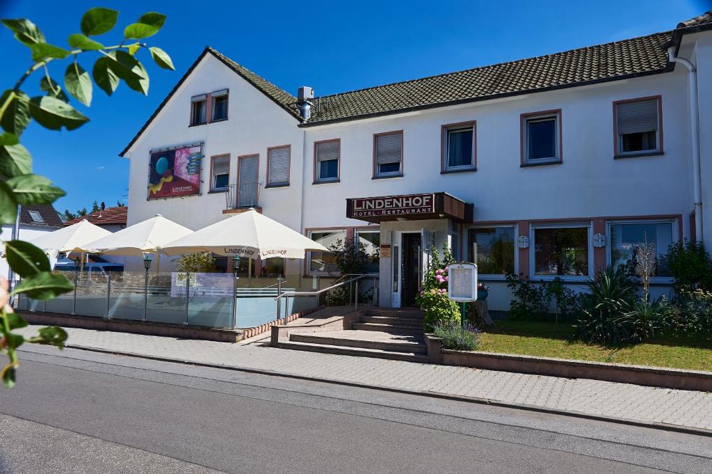 ein Gebäude mit Sonnenschirmen an der Straßenseite in der Unterkunft Hotel Restaurant Lindenhof in Biblis