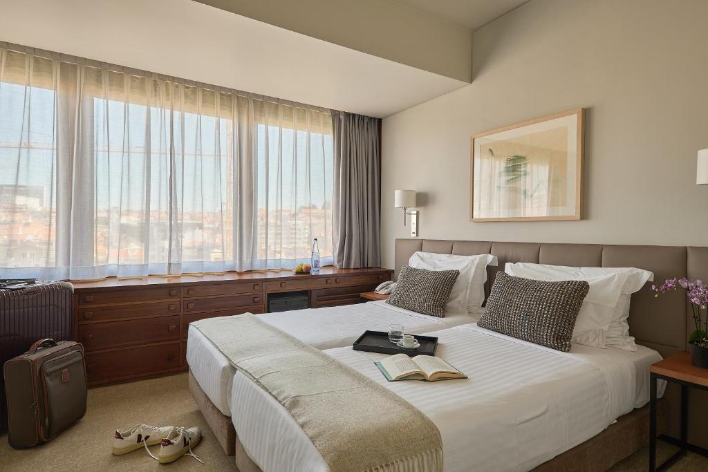 Pokój hotelowy z dużym białym łóżkiem i oknami w obiekcie Hotel Dom Carlos Park w Lizbonie