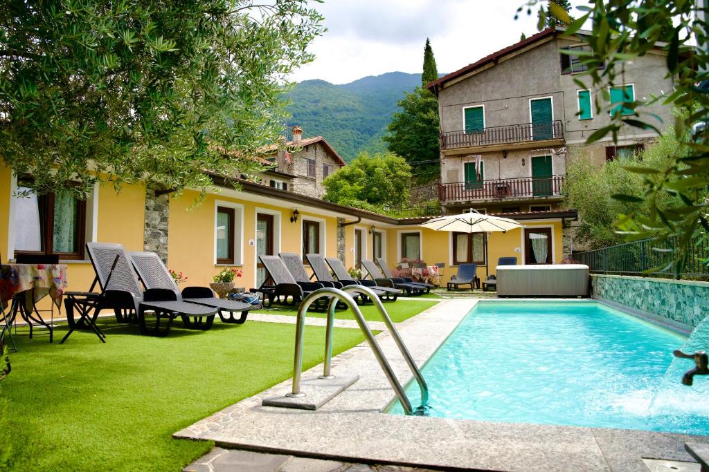 a swimming pool in a yard with chairs and a building at Il Portichetto in Perledo