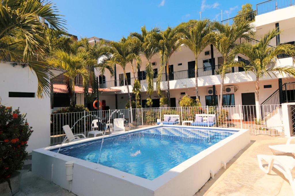 a pool in the courtyard of a hotel with palm trees at Hotel Zulan in Tolú