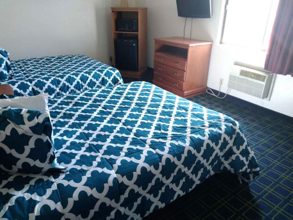 Un dormitorio con una cama azul y blanca y un tocador en Sunset Inn and Suites, en Seward