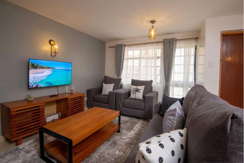 a living room with a couch and a tv at Athi Luxury Suites in Athi River
