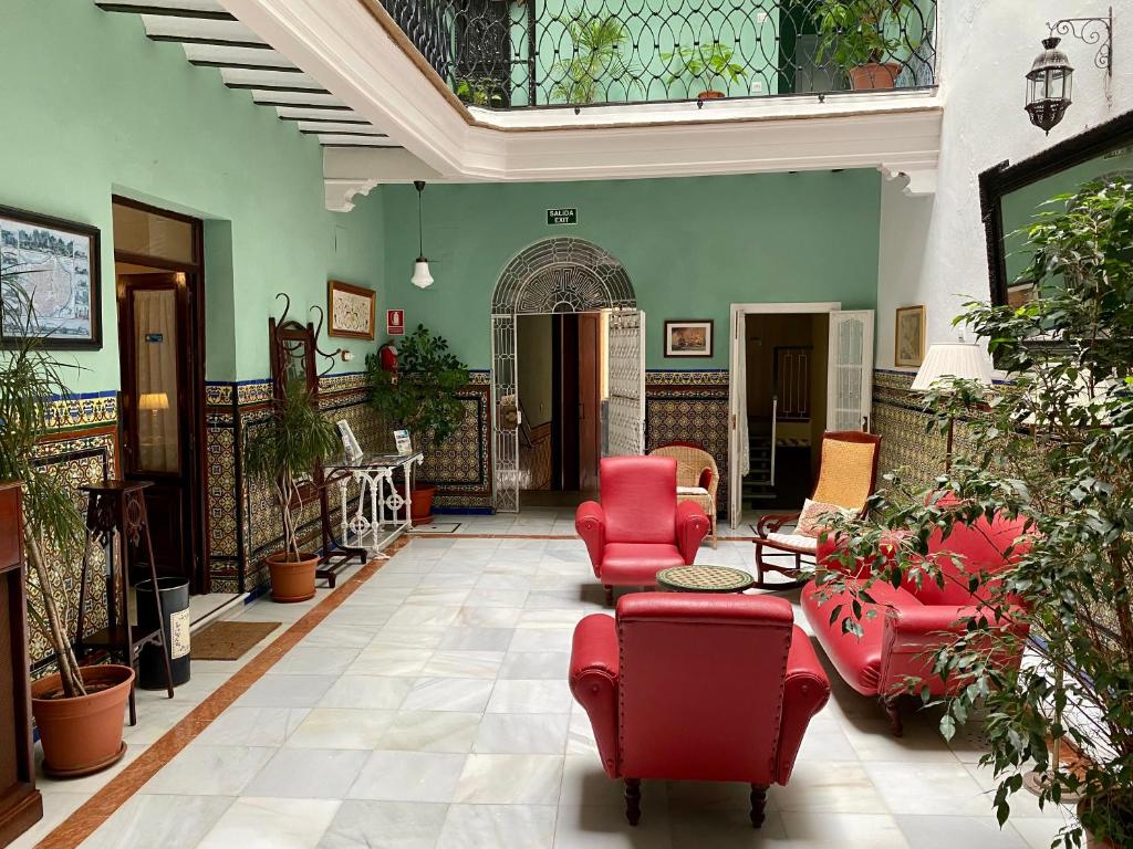 un grand salon avec des meubles rouges et des plantes dans l'établissement Pensión España, à Cadix