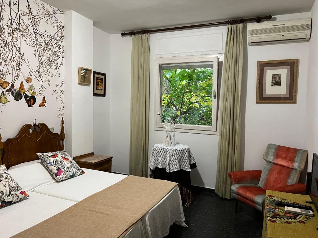 Un dormitorio con una cama y una ventana y una silla. en Hostal Pirineos, en Barbastro