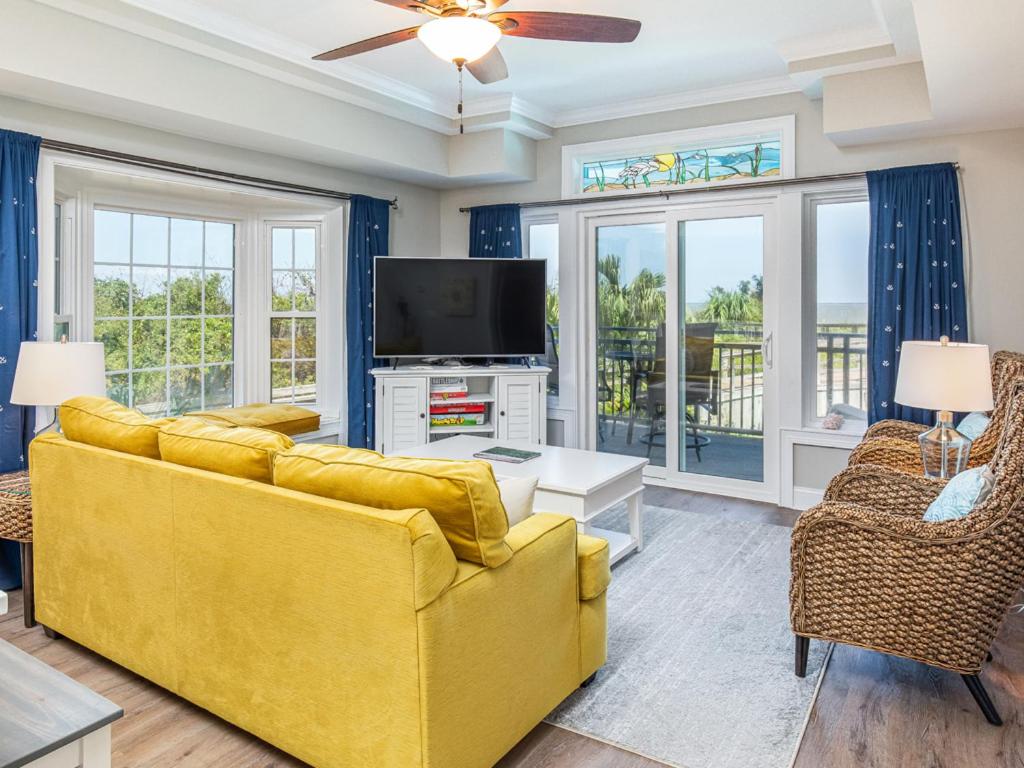 a living room with a yellow couch and a tv at Bay View Villas 105 in Tybee Island