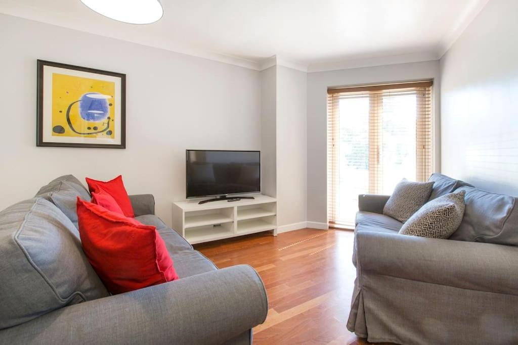 a living room with two couches and a flat screen tv at Cosy Modern Oxford Apartment in Oxford