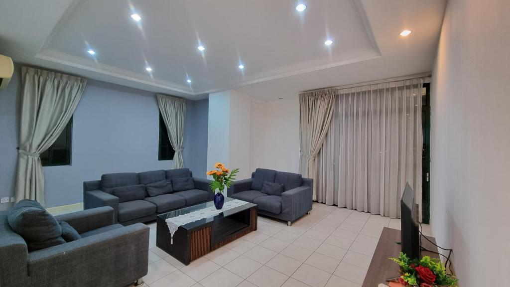 sala de estar con sofás azules y TV en Kenyalang Emerald Riverine Resort Homestay, en Kuching