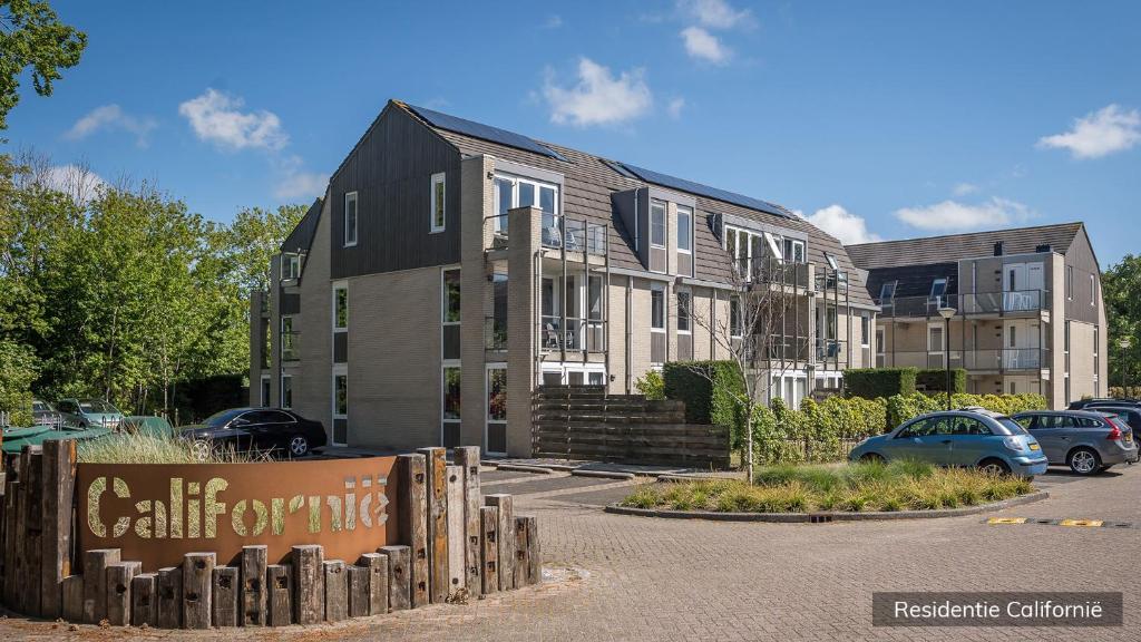 een gebouw met auto's geparkeerd op een parkeerplaats bij Residentie Californië in De Koog