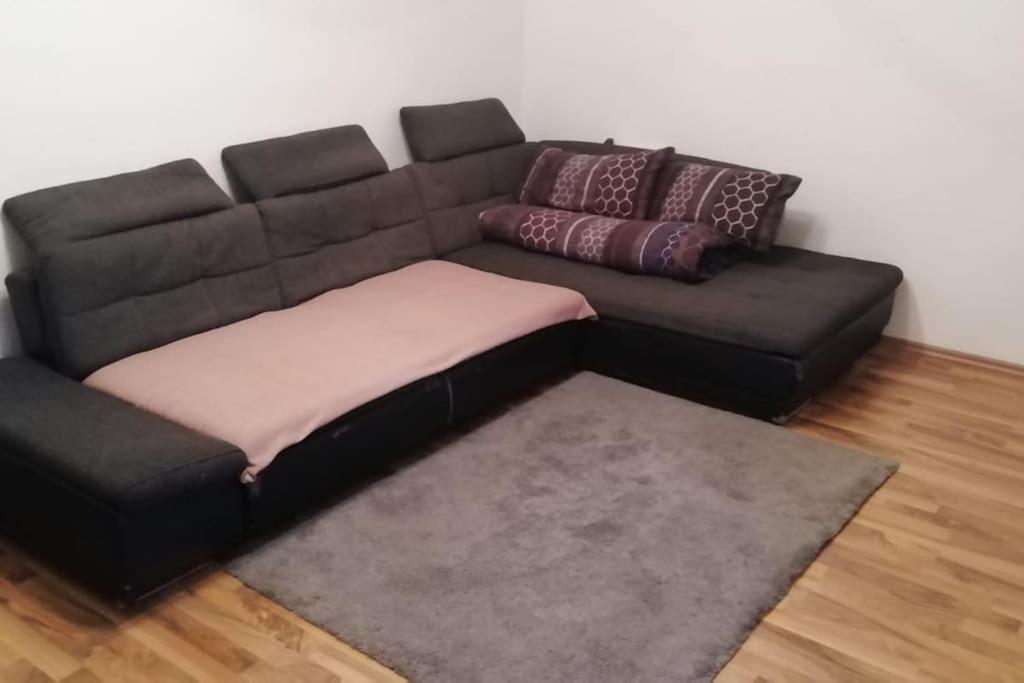 ein schwarzes Sofa mit Kissen darauf im Wohnzimmer in der Unterkunft Nice and cozy 1 room apt in Wiesbaden