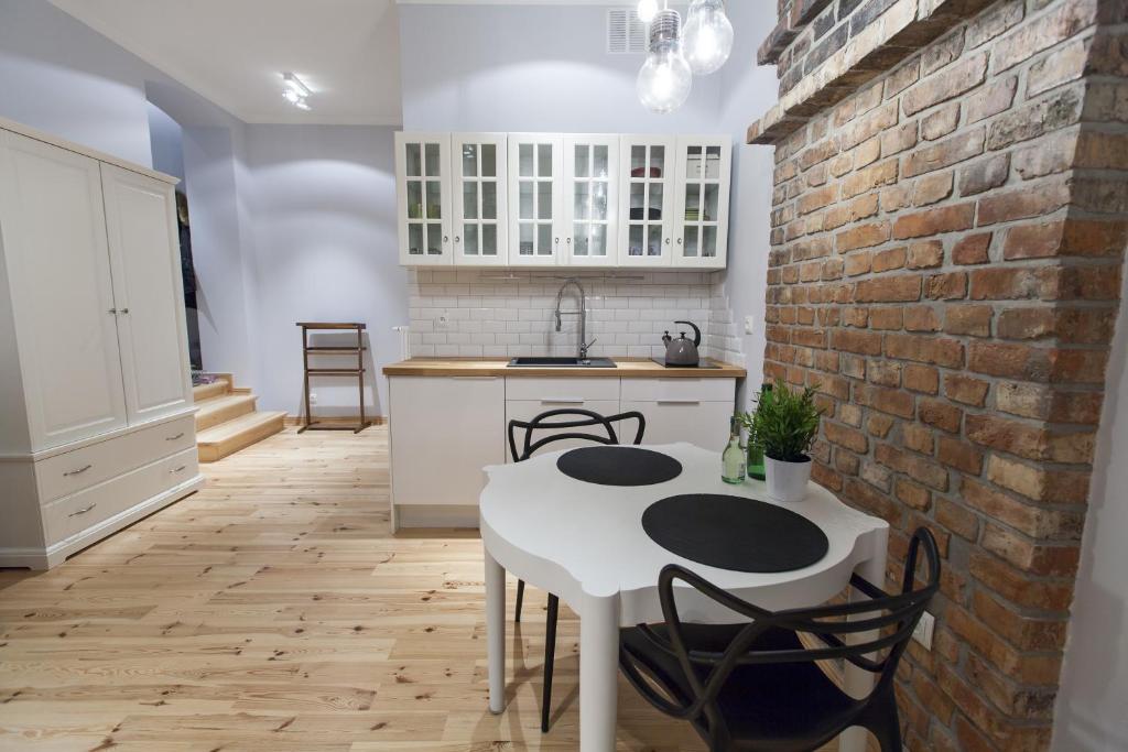 uma cozinha com uma mesa e cadeiras brancas e uma parede de tijolos em Homewell Apartments Pod Szczerbatym em Poznań