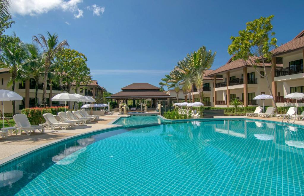 einen Pool in einem Resort mit Stühlen und Sonnenschirmen in der Unterkunft The Leaf Oceanside by Katathani - SHA Extra Plus in Khao Lak