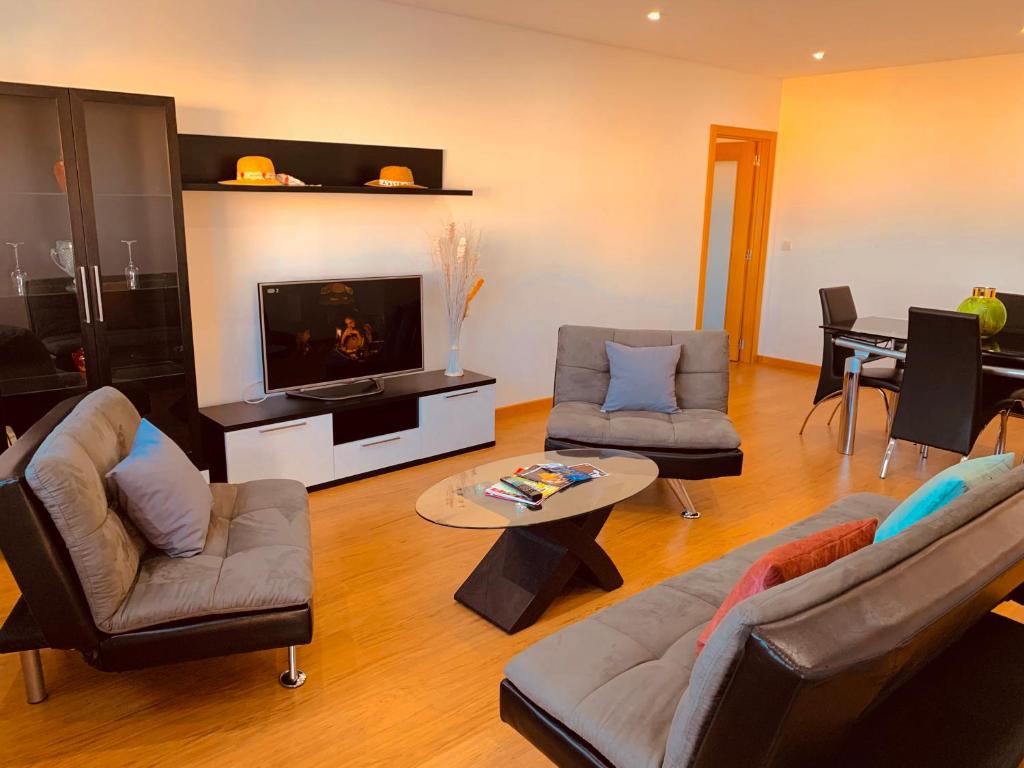 uma sala de estar com um sofá e cadeiras e uma televisão em Apartamento ALTAMIRA T2 SERRA SHOPPING na Covilhã
