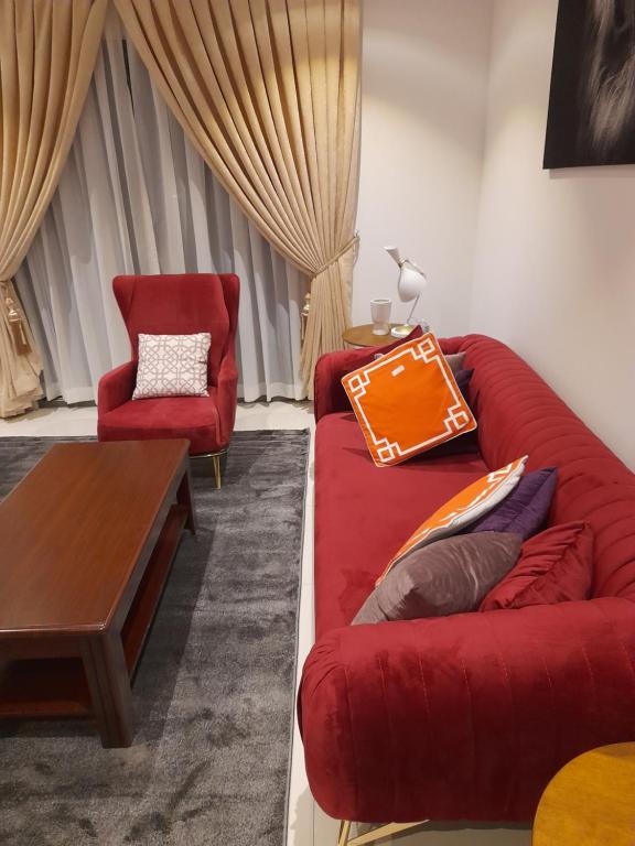 a living room with a red couch and a chair at The Lennox D-Plus Apartments in Accra