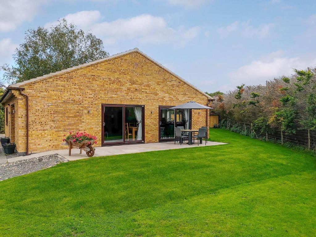 una casa de ladrillo con un césped verde delante de ella en Grange Garth Cottage en Acaster Malbis