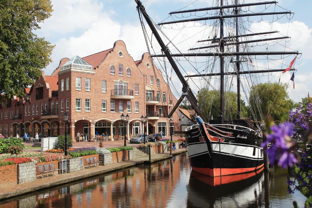 a boat in a canal in front of a building at Arkadenhaus - Hotel Freiherr von Schwarzenberg in Papenburg