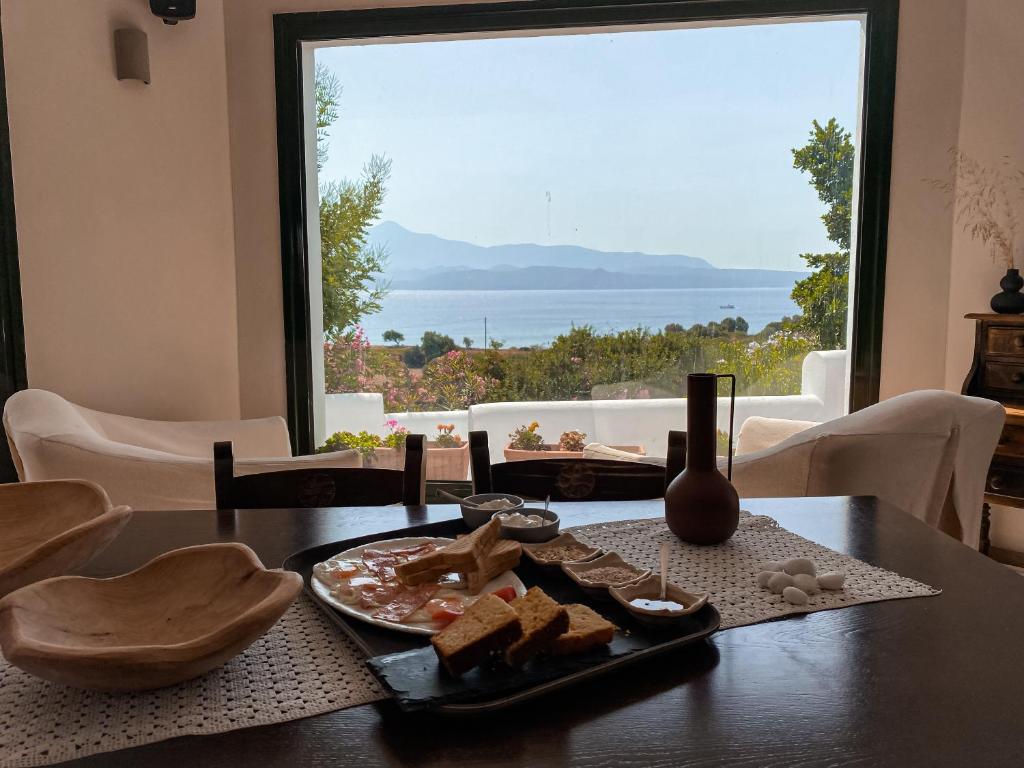 a table with a plate of food and a large window at Nisea Hotel Samos in Pythagoreio