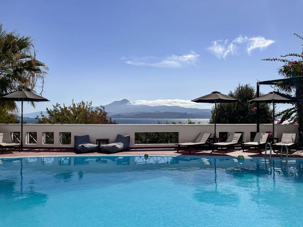 a large blue swimming pool with chairs and umbrellas at Nisea Hotel Samos in Pythagoreio