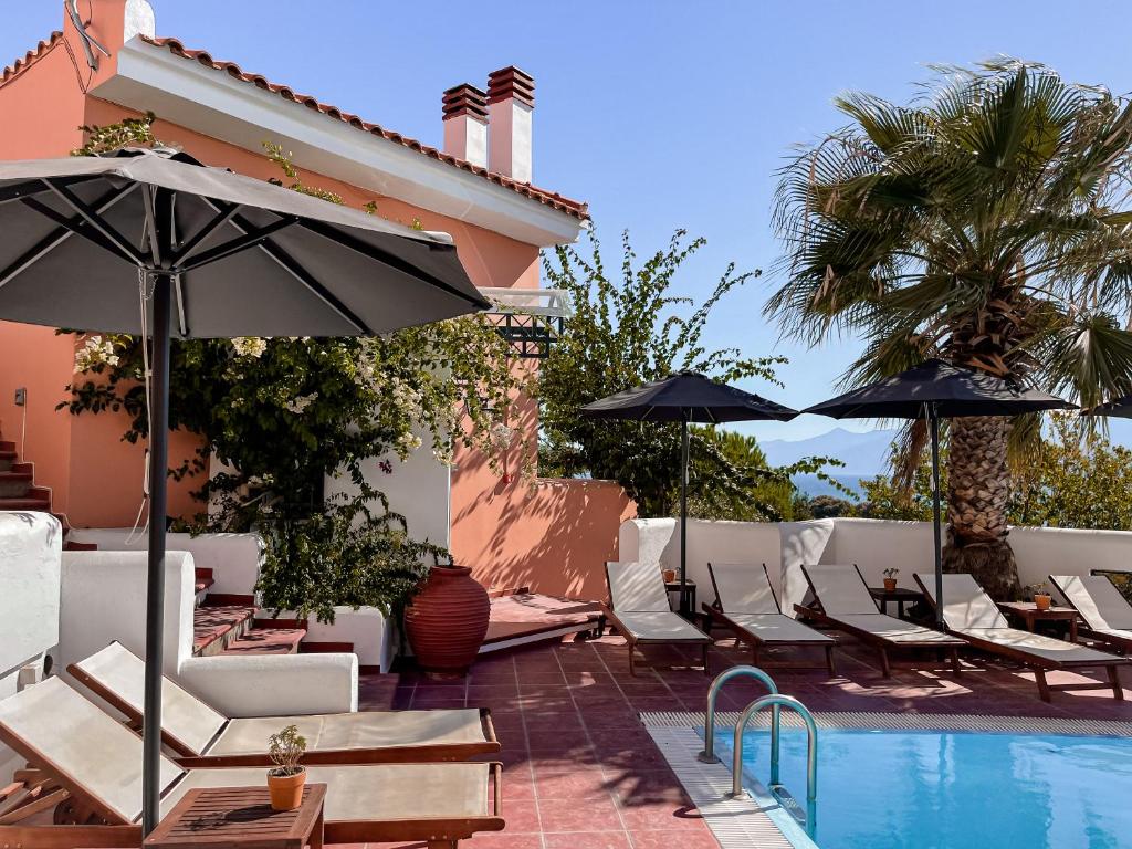 a pool with chairs and umbrellas next to a building at Nisea Hotel Samos in Pythagoreio