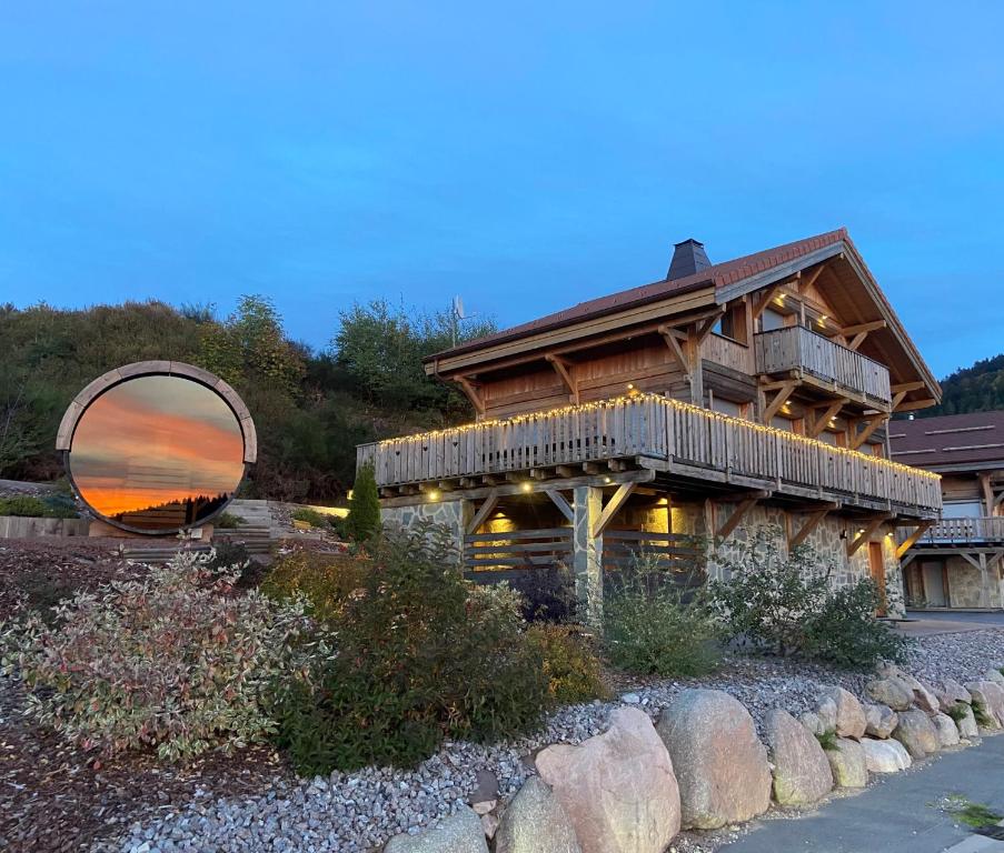 a large log house with a mirror on the side of it at Chalet des Cîmes, chaleureux avec jacuzzi et sauna in Gérardmer