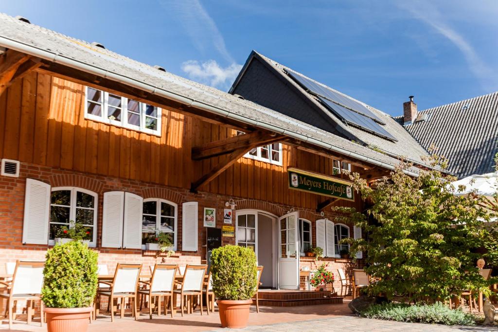 um edifício de madeira com cadeiras em frente em Meyers Hofcafe em Isenbüttel