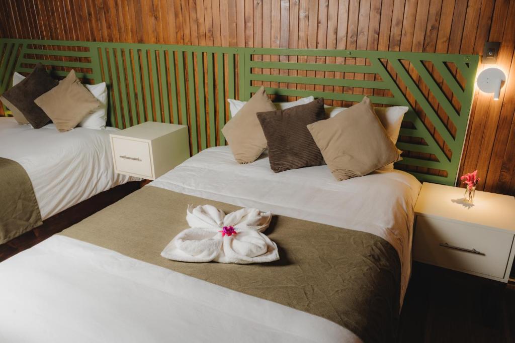 Habitación de hotel con 2 camas con una flor en la cama en Lauraceas Lodge, en San Gerardo de Dota