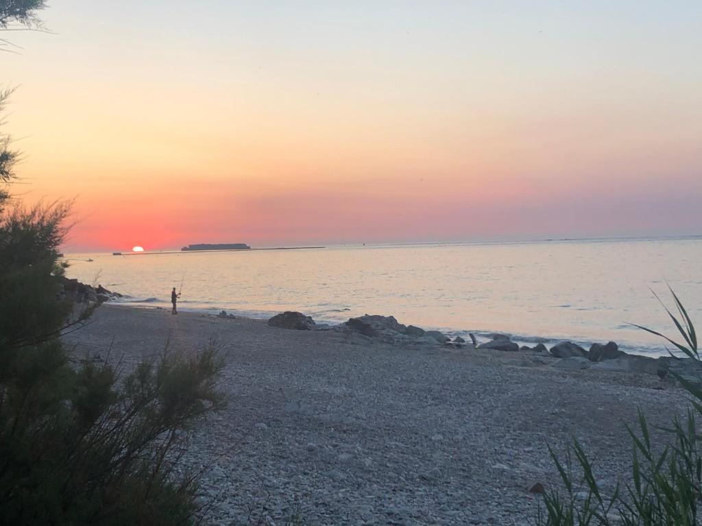 a beach at sunset with a person standing on the shore at Sur le chemin de la plage in Cherbourg en Cotentin