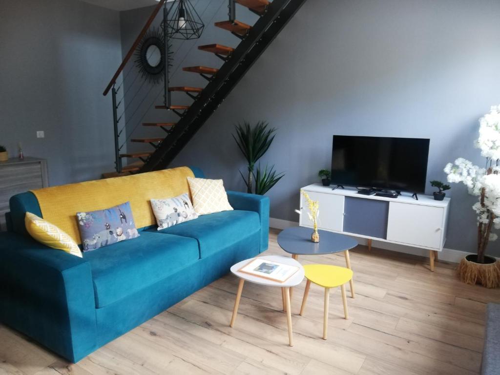 a living room with a blue couch and a tv at Les Terrasses du Pigeonnier, Duplex 4 pers en Baie de Somme in Vron