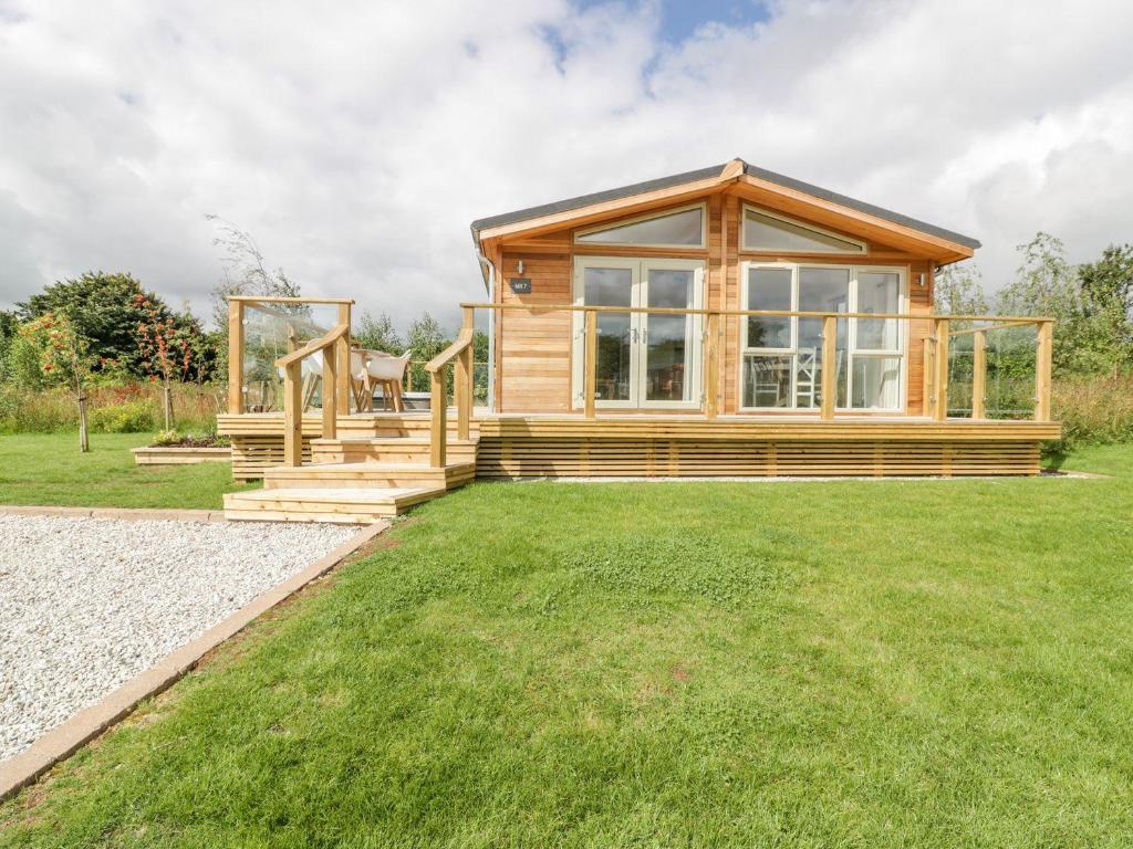 a log home with a large window and green grass at 7 Meadow Retreat in Liskeard