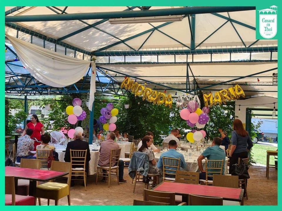 a group of people sitting at tables under a tent with balloons at Conacul cu Nuci 