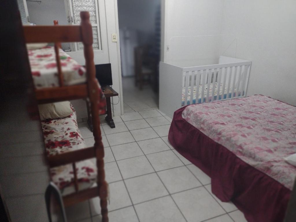1 dormitorio con 1 cama, 1 silla y 1 cuna en Kitnet completa en Guaratinguetá