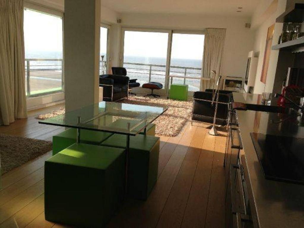 - un salon avec une table en verre et une vue sur l'océan dans l'établissement The Lighthouse, à Coxyde