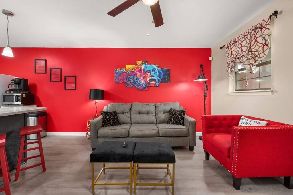 sala de estar con sofá y pared roja en HEIRS LIVING : BEAUX - Near Cabrini Hospital . Colleges . 3TVs . Free Parking . Pet Friendly . 2BR Fully Furnished, en Pineville