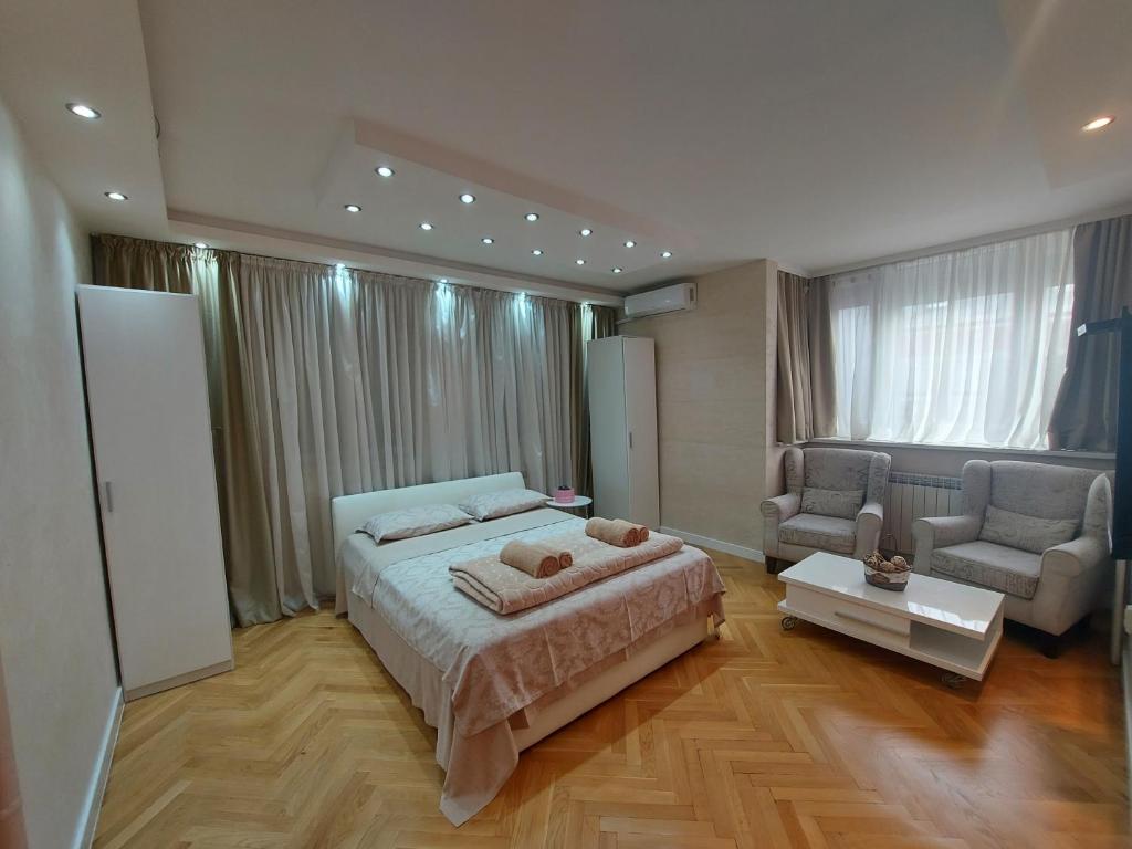 a bedroom with a bed and a couch and a chair at Arena Relax Apartman in Belgrade