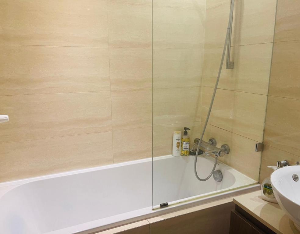 a bathroom with a shower with a tub and a sink at City Centre Platinum Towers Apartment in Warsaw